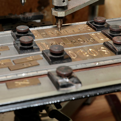 Pantograph engraver with brass tiled letters in tray.